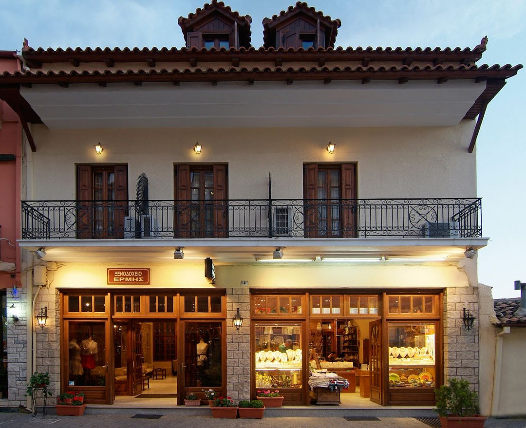 A building with a ground floor that has shops in it and above it is a lined balcony with three slatted doors