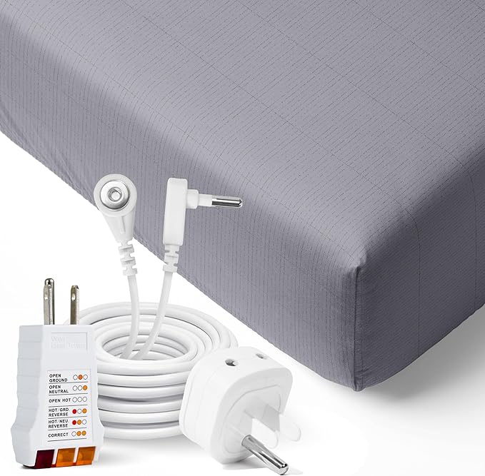 A close up of 2 wall socket adapters and a cord coiled neatly to form a circle and the metal power conductor protrudes in the middle so to be highlighted. A background of the edge of a well fitted sheet.