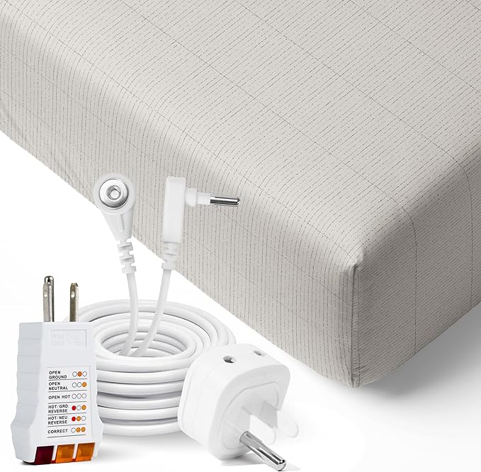 A close up of 2 wall socket adapters and a cord coiled neatly to form a circle and the metal power conductor protrudes in the middle so to be highlighted. A background of the edge of a well fitted sheet.