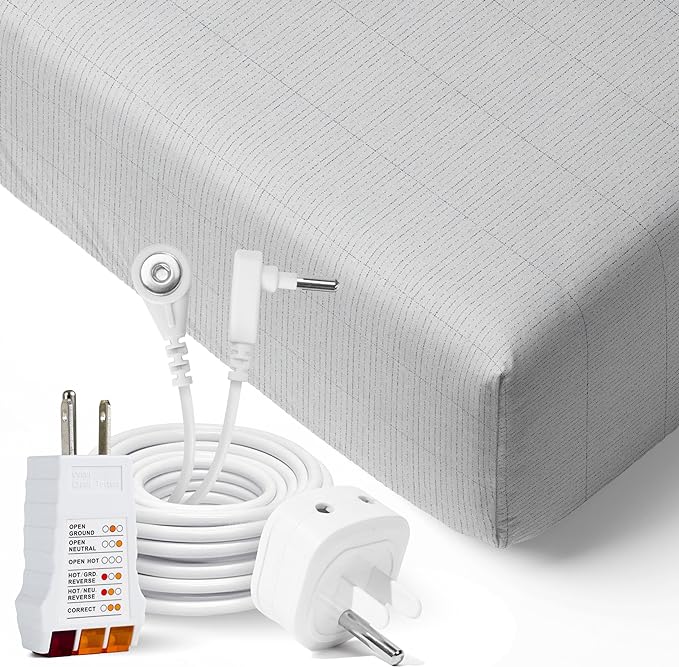A close up of 2 wall socket adapters and a cord coiled neatly to form a circle and the metal power conductor protrudes in the middle so to be highlighted. A background of the edge of a well fitted sheet.