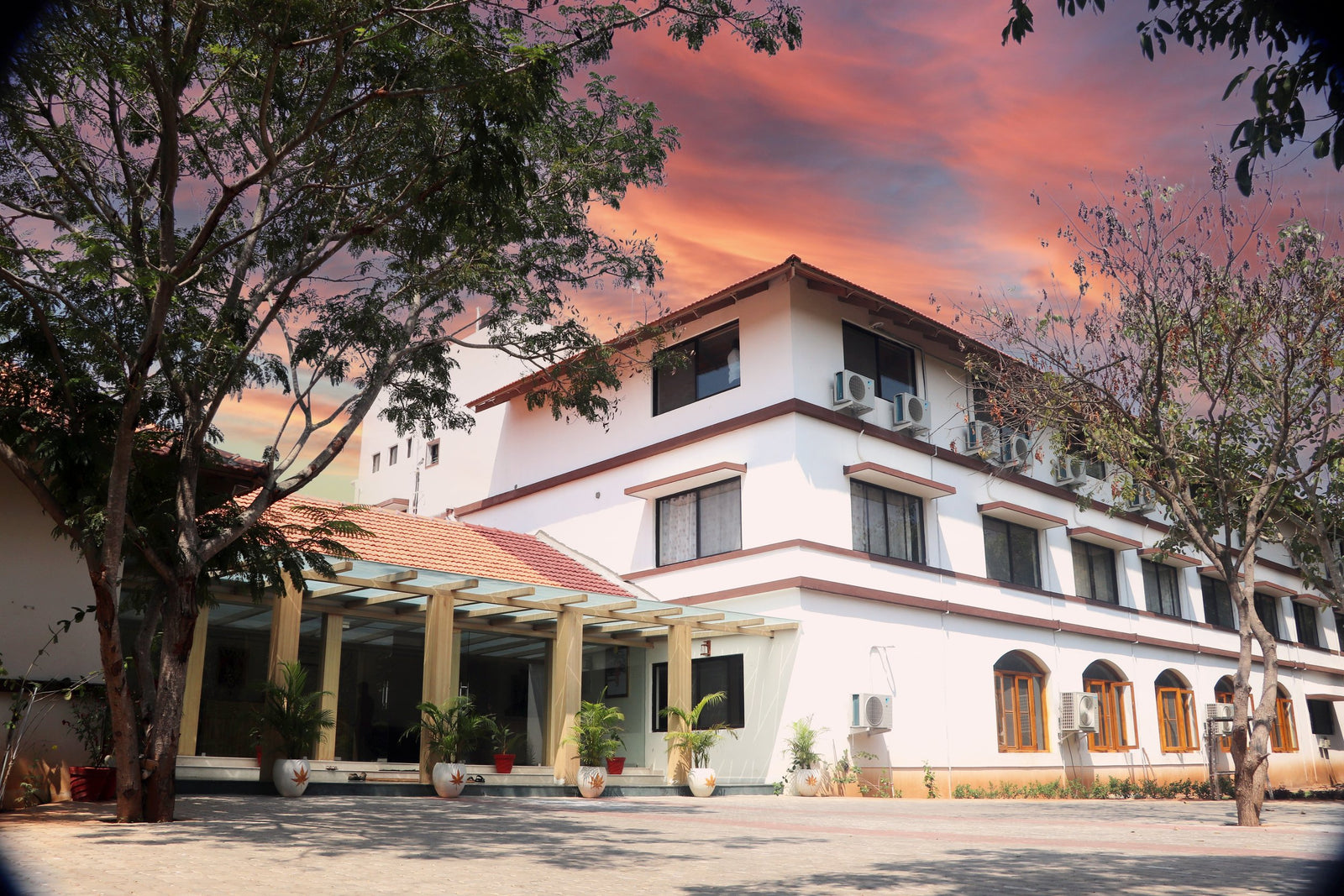 A building structure where there's a lanai and a three floored building with a  colored sky.