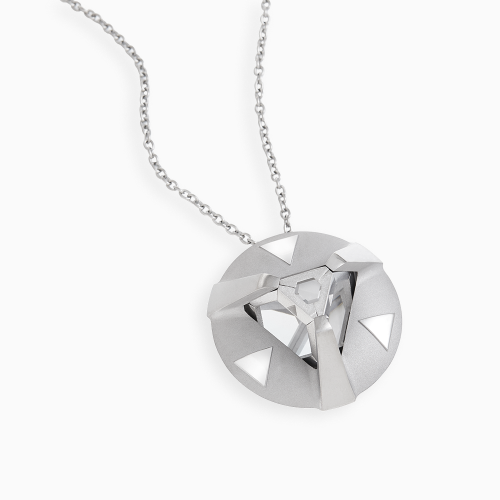 A close up in flat lay of a circular silver pendant on a  on a necklace with a crystal in the middle lodged in the 3 prongs and with shiny triangles in between spaces of the prongs.