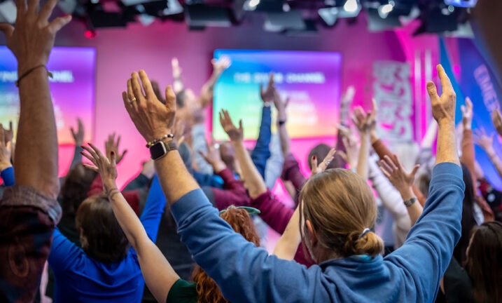 Back view of the people in a conference with their hands up high