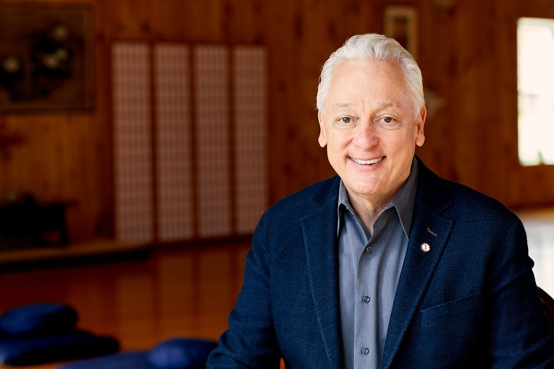 A blurred wall made of wood as the background and a smiling man is in the foreground