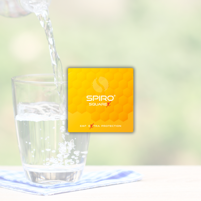 A yellow square with honeycomb design in the background with small spaced lines and a text that says Spiro square x EMF extra protection and a very faint background of it of water being poured on a glass