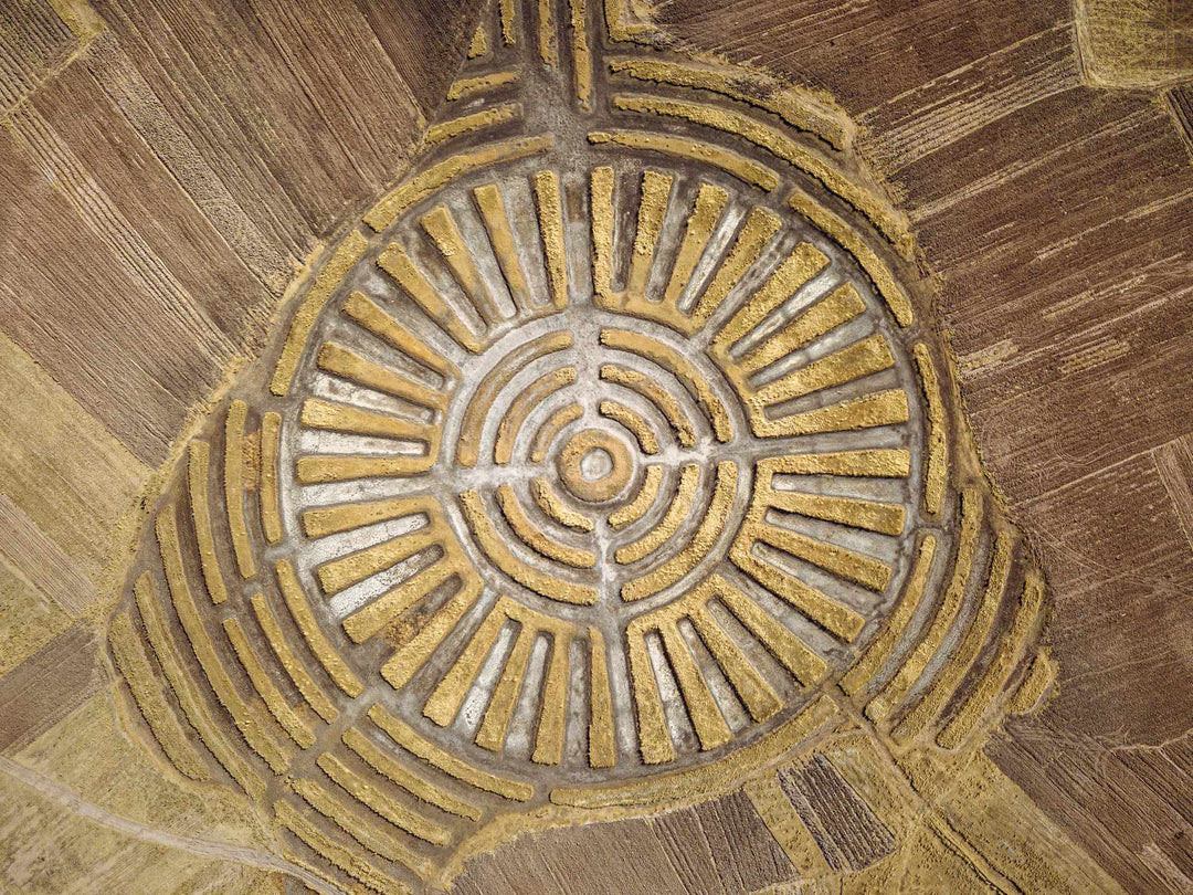 A large field with a crop circle that looks like a water dropped in the middle, spreading out 