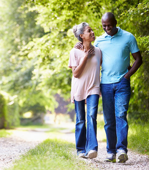 couple walking with arms around each other in a nature trail