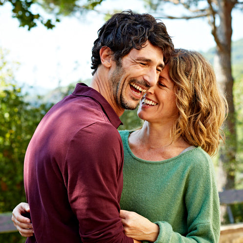 A close up of a couple laughing while embracing each other