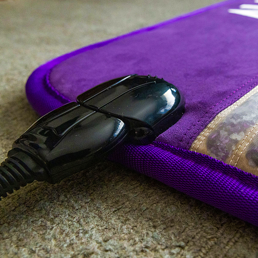 A close up of the power cord head attached to the mat's power receiver placed on the carpeted floor