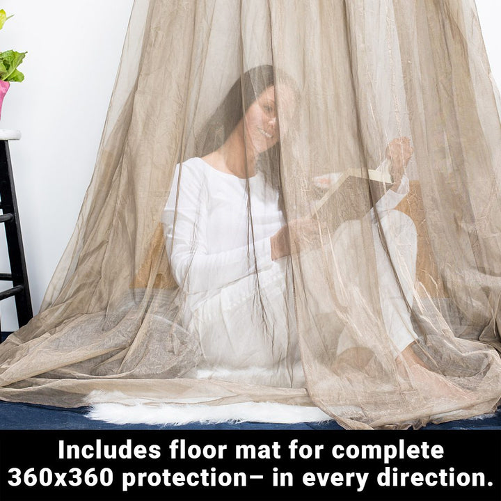 A woman sitting on the floor, reading a book inside an enclosed draped fabric that hangs above. The text below says, includes floor mat for complete 360x360 protection - in every direction.