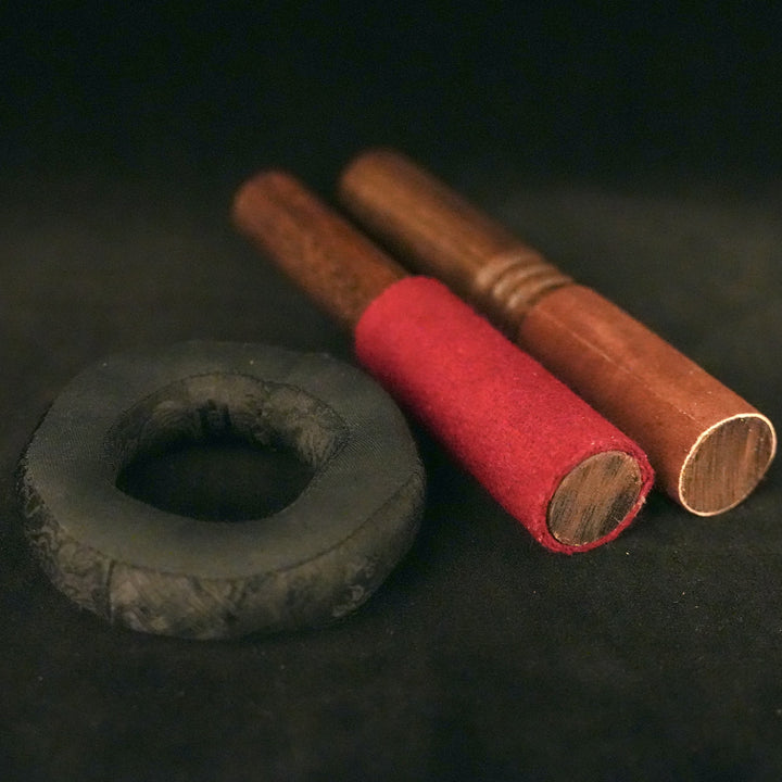 A small, round pillow with a hole in the middle, beside it are two wooden sticks